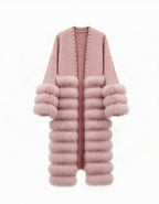 A long open-front cardigan in dusty pink, featuring a smooth knit upper section, a thick faux-fur collar, and stacked faux-fur sleeve cuffs and hem, with small metallic studs along the front opening.