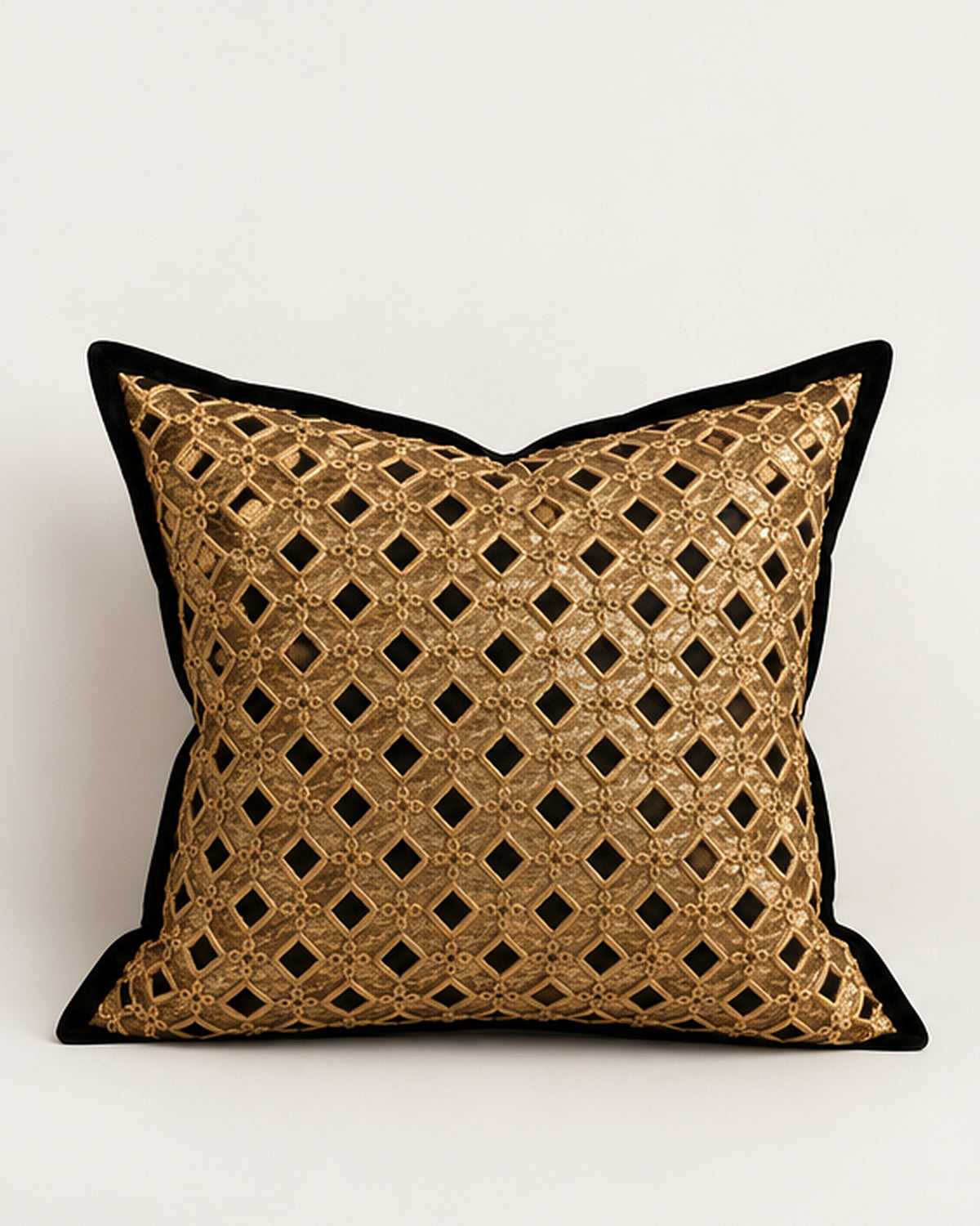 A square decorative throw pillow featuring a gold metallic geometric lattice pattern with black diamond cutouts, finished with a solid black velvet border, set against a plain light gray background.