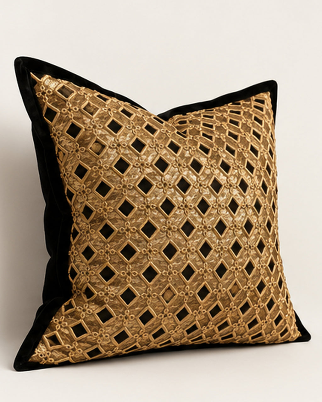 A square decorative throw pillow with a black velvet border and a gold metallic geometric lattice pattern on a light neutral background.