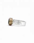 Gold ring with green gemstones and small diamonds on a white background
