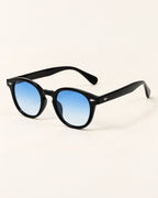 Black round-frame sunglasses with blue gradient lenses, displayed on a clean off-white background.
