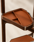 Close-up of a wooden storage tray with a terracotta-colored interior, mounted on a dark wood furniture piece against a soft beige background.