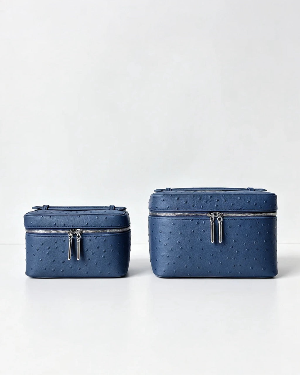 Two blue textured zippered cosmetic bags in different sizes, displayed side-by-side on a clean white surface against a light gray background.