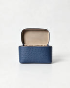 A blue ostrich-textured leather jewelry box with an open lid showing a beige interior, set against a plain white background.
