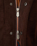 Close-up of a dark brown textured jacket with a silver metal zipper and snap buttons.