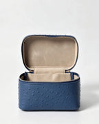 A blue textured faux-ostrich leather cosmetic case with an open lid, showing a beige interior lining, set against a plain light gray background.