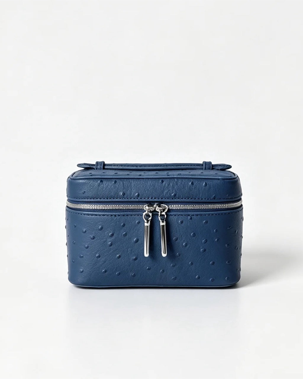A navy blue faux ostrich leather cosmetic case with silver zipper pulls, photographed on a clean white background.