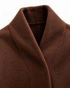 Close-up of a brown shawl collar coat or jacket, showing the soft textured fabric and folded collar detail against a plain white background.