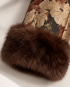 Close-up of a dark brown faux fur trim attached to a beige and brown floral brocade fabric cuff.