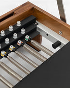 Close-up of a wooden-framed heating or ventilation unit showing black metal baffles, white plastic caps, and multiple corrugated metal ducts connected with colored connectors.