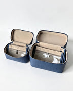 Two navy blue textured organizer cases with beige interiors and clear zippered pockets, shown open on a light gray background.