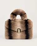 A structured faux fur handbag with a rounded top handle, featuring alternating vertical stripes of light brown, black, and beige, and a snake-head clasp at the center.