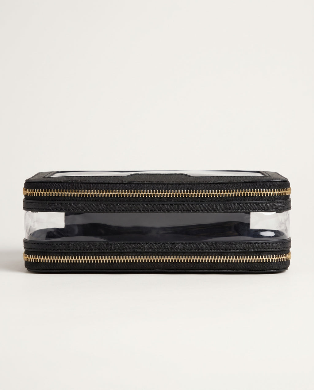 A rectangular black zippered pouch with clear plastic front panels and gold-tone zippers, shown against a plain off-white background.