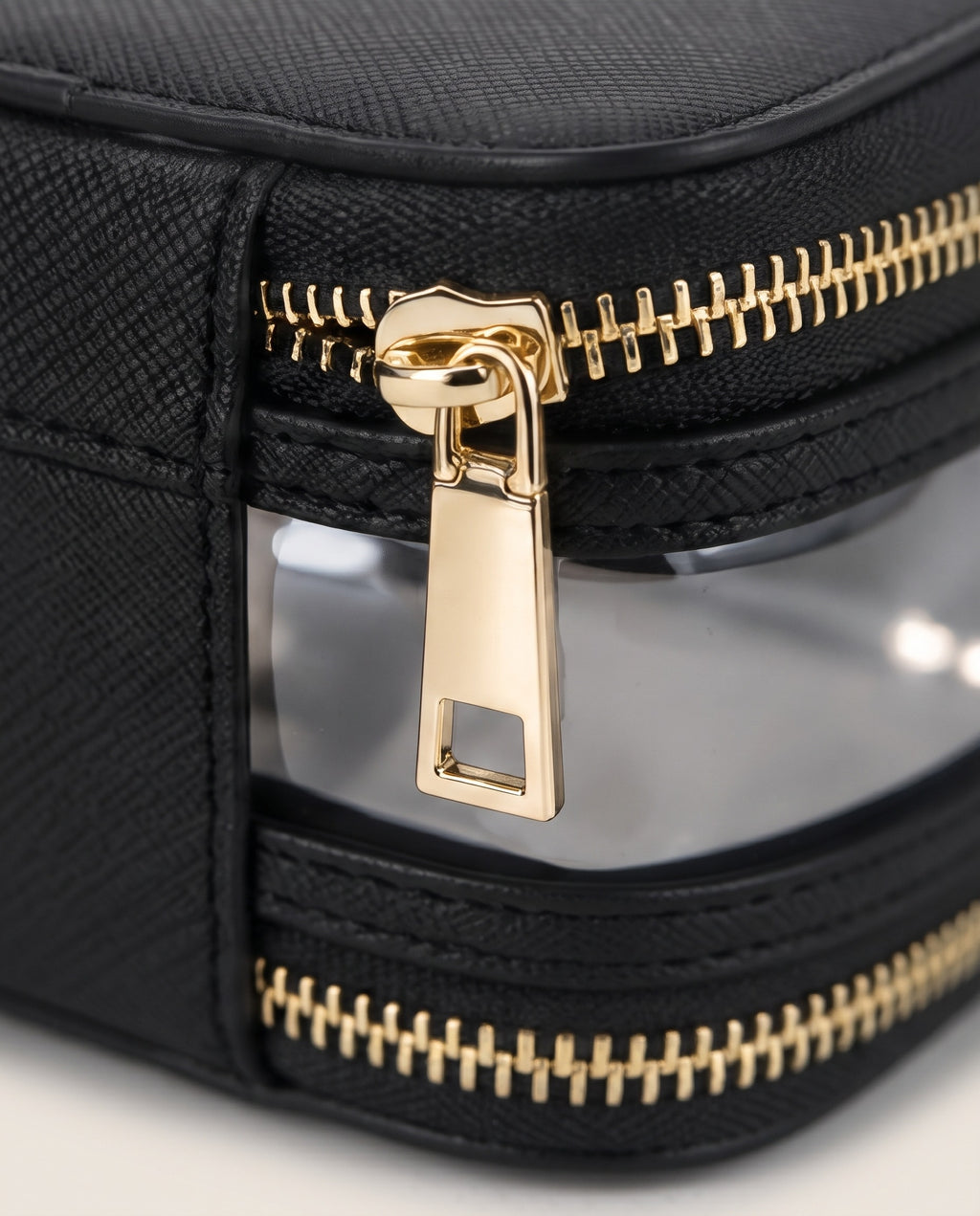 Close-up of a black textured zippered pouch with a clear window and shiny gold zipper pulls.