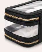 Black textured toiletry bag with clear plastic windows and gold-tone zippers, shown in a close-up studio shot on a light background.
