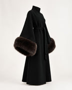 A black long coat with wide sleeves and dark brown fur trim at the cuffs, shown on a plain light background.