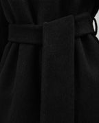 Close-up of a black belted coat or dress fabric, showing the waist tie and soft textured material.