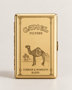 A gold-toned Camel Filters tin for Turkish & Domestic Blend, featuring an engraved camel illustration and branding on a light gray background.