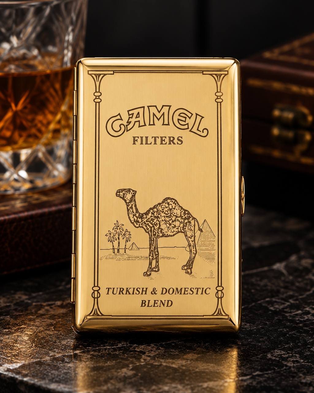 A gold Camel Filters tin for Turkish and Domestic Blend tobacco, featuring an engraved camel illustration, displayed on a dark marble surface with a glass of amber liquid in the background.