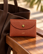 The Mayfair Card Purse in brown against a leather bag