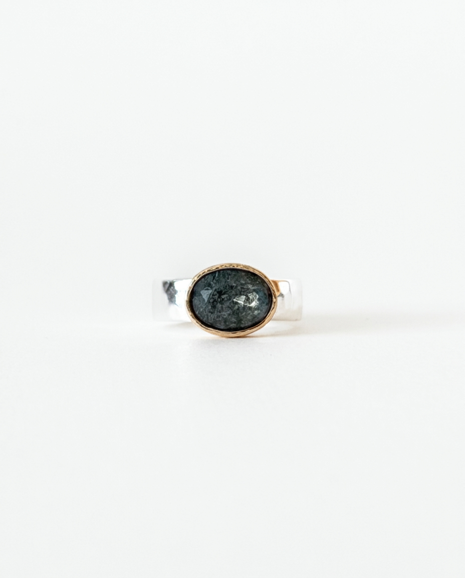 Silver ring with a dark gemstone on a white background