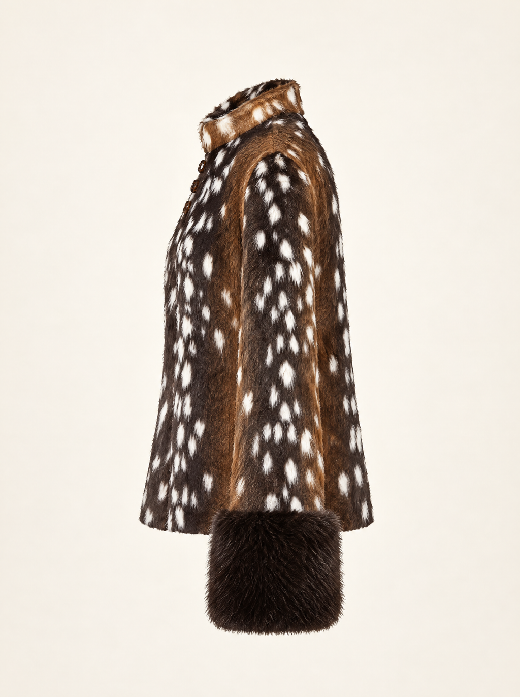A side-profile view of a brown and white spotted fur coat with a dark brown fur cuff, set against a solid off-white background.