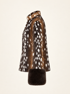 A side-profile view of a brown and white spotted fur coat with a dark brown fur cuff, set against a solid off-white background.
