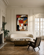 A large framed abstract painting with bold red, black, cream, and blue shapes hangs on a cream paneled wall above a curved white sofa in a bright, elegant living room with wood herringbone flooring.