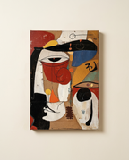 An abstract cubist-style painting on canvas, featuring stylized faces and geometric shapes in black, white, red, blue, yellow, and brown tones, displayed against a warm off-white wall.