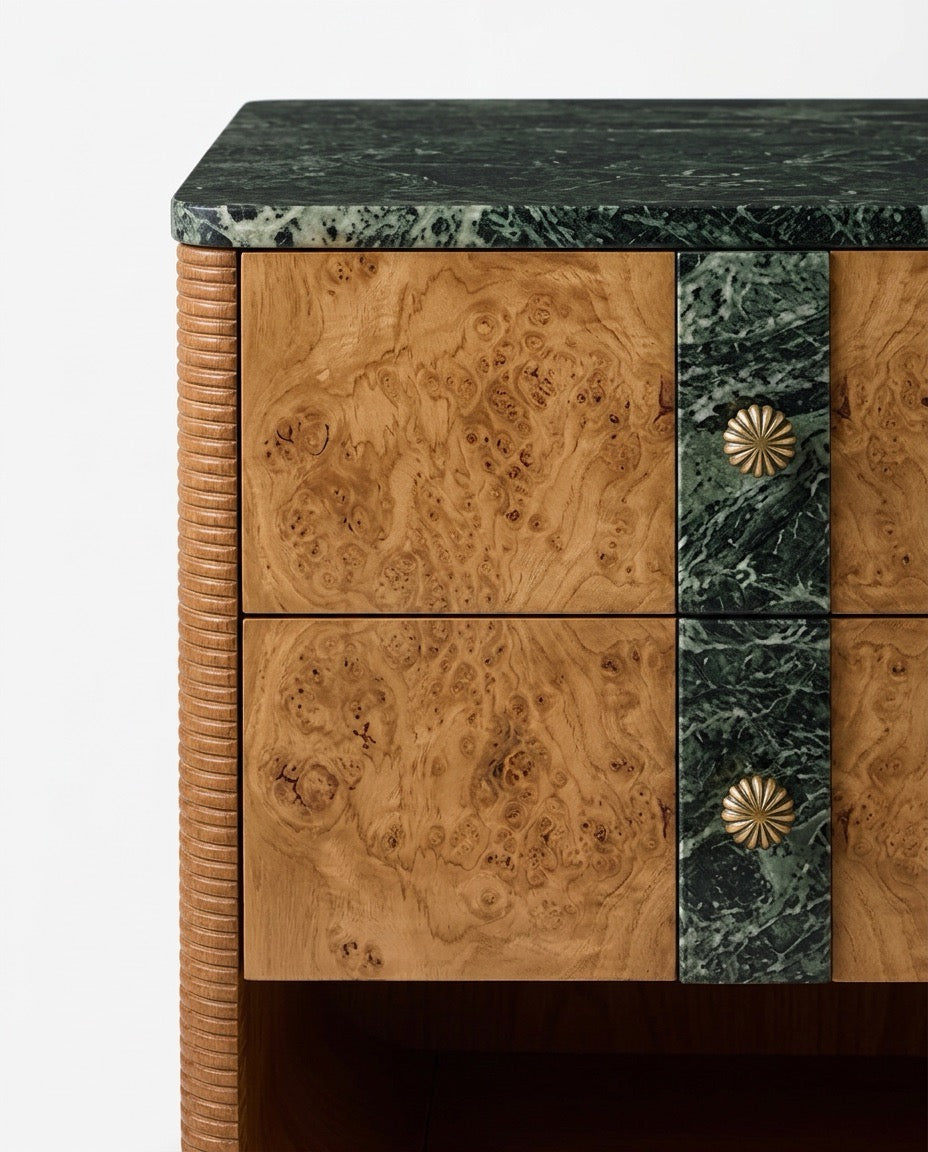 Close-up of a wooden cabinet or sideboard with two drawers, featuring natural burl wood fronts, dark green marble panels and top, and round metallic sunburst drawer pulls.