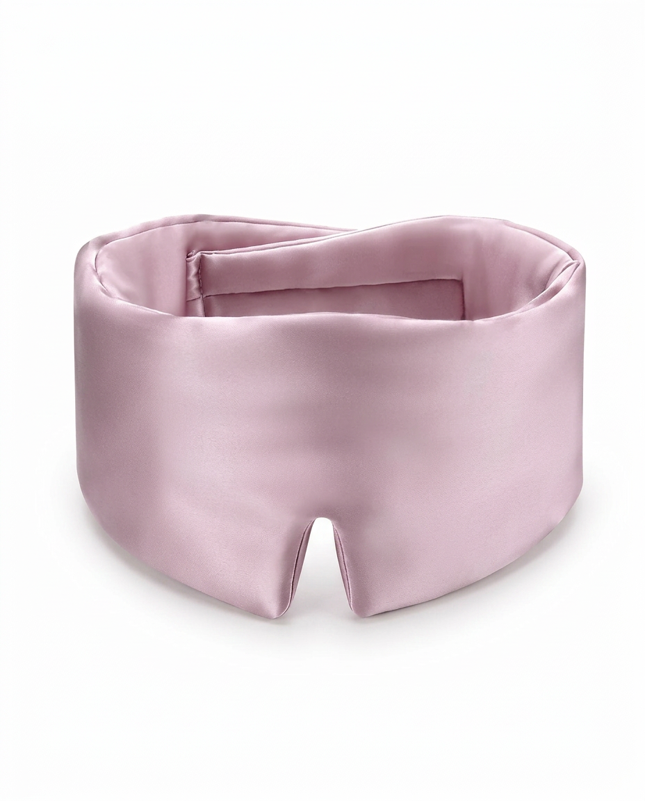 A light pink satin sleep mask with a wide padded band and a central cutout, displayed on a clean white background.