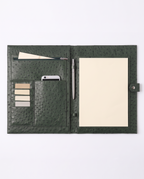 An open dark green ostrich-textured leather organizer cover, shown flat against a white background. The cover features multiple card slots holding beige and silver cards, a pen loop holding a silver pen, and a large cream-colored notepad on the right side.