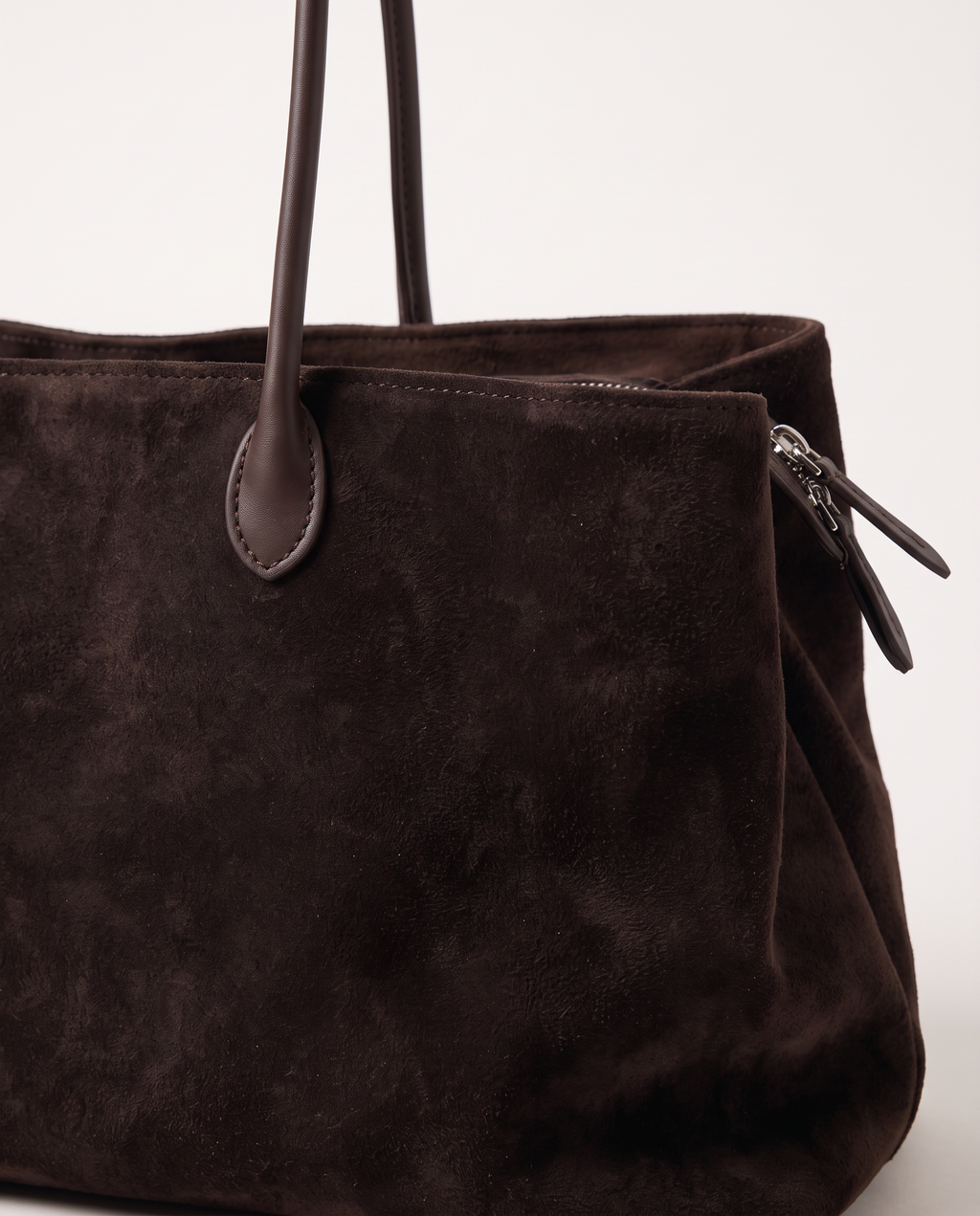 Close-up of the Dark Coffee suede, leather handle tab and side zip on The Marais Tote