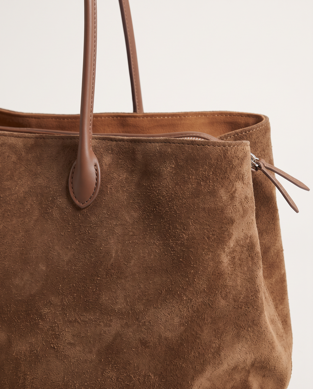 Close-up of the Brown suede, leather handle tab and side zip on The Marais Tote