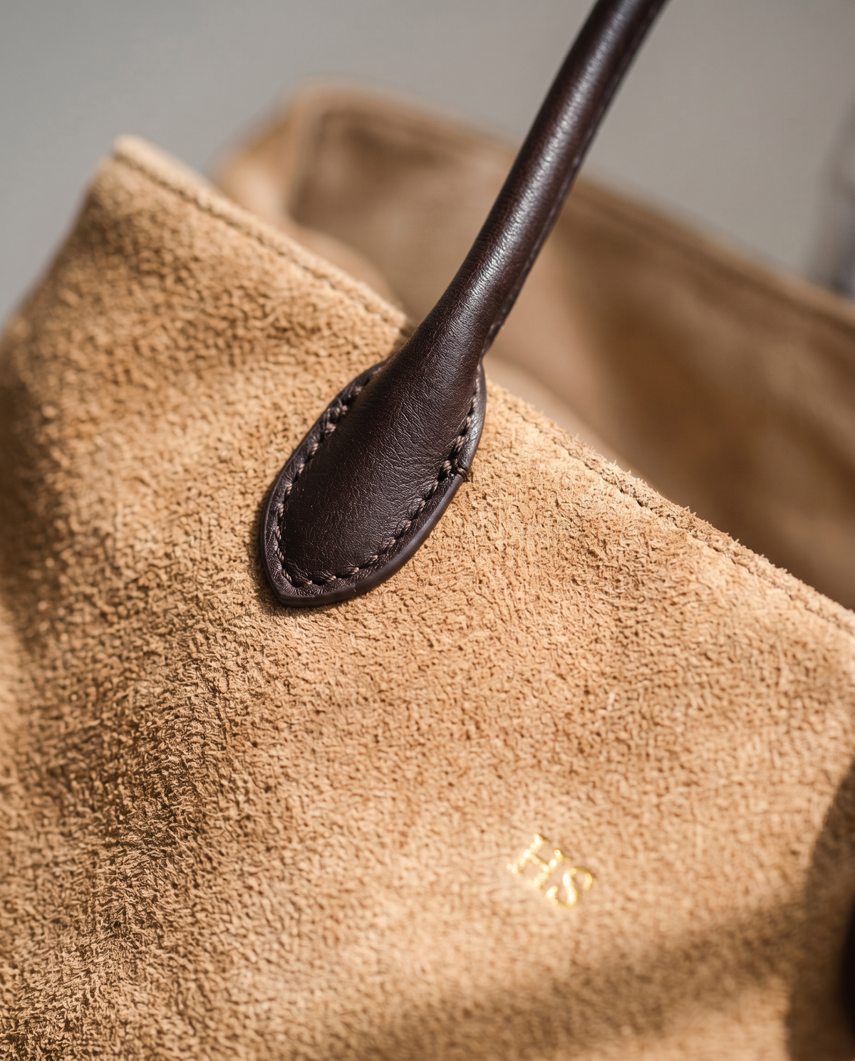 Close-up of the Apricot suede nap, leather handle tab and gold embossed initials on The Marais Tote