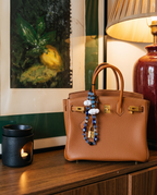 The Daydream strap tied to the handle of a tan leather bag on a sideboard