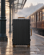 The Meridian Suitcase in black with brown on a railway platform