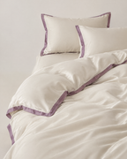 The Lyon Silk Bedding Set in cream with mauve border, unmade