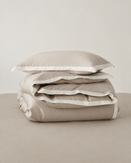 The Lyon Silk Bedding Set in oyster with ivory border, folded