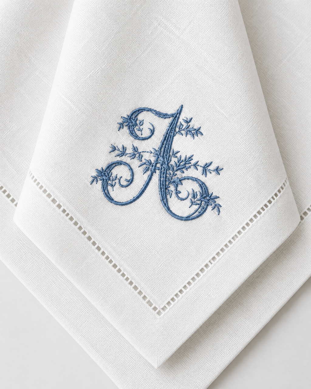 The Belle Époque Napkin, close-up of an embroidered floral initial on a hemstitched napkin corner