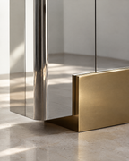 Close-up of the mirror-polished steel and gold-finish base on The Mercury Cabinet