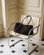 The Marais Tote in dark coffee suede on a chrome chair