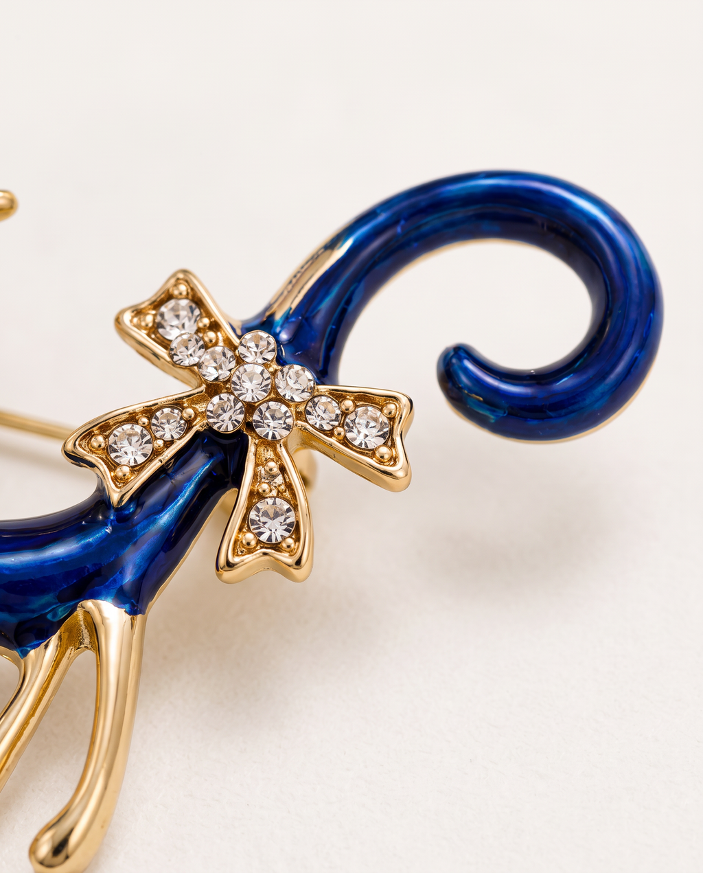 Close up of the curled blue enamel tail and rhinestone bow
