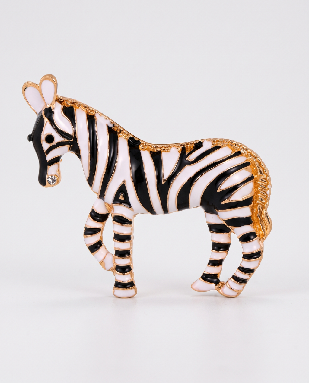 The Zebra Brooch in black and white enamel with gold on an off-white background