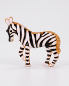 The Zebra Brooch in black and white enamel with gold on an off-white background