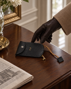 Reaching for The Concierge Key Pouch in black leather on a walnut hallway table