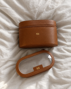The Riviera Vanity Case in tan with gold initials on off-white linen