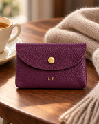 The Mayfair Card Purse in purple on a wooden table with coffee