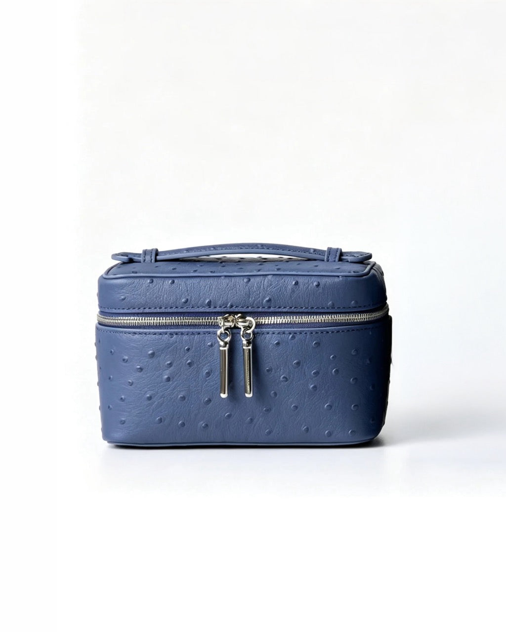 A blue ostrich-textured leather cosmetic case with a top handle and silver-tone zipper pulls, photographed against a clean white background.