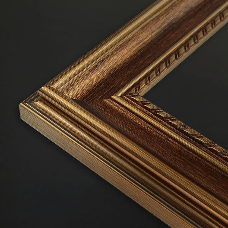 Close-up of a decorative picture frame corner showing layered woodgrain in dark brown and warm gold tones against a dark background.